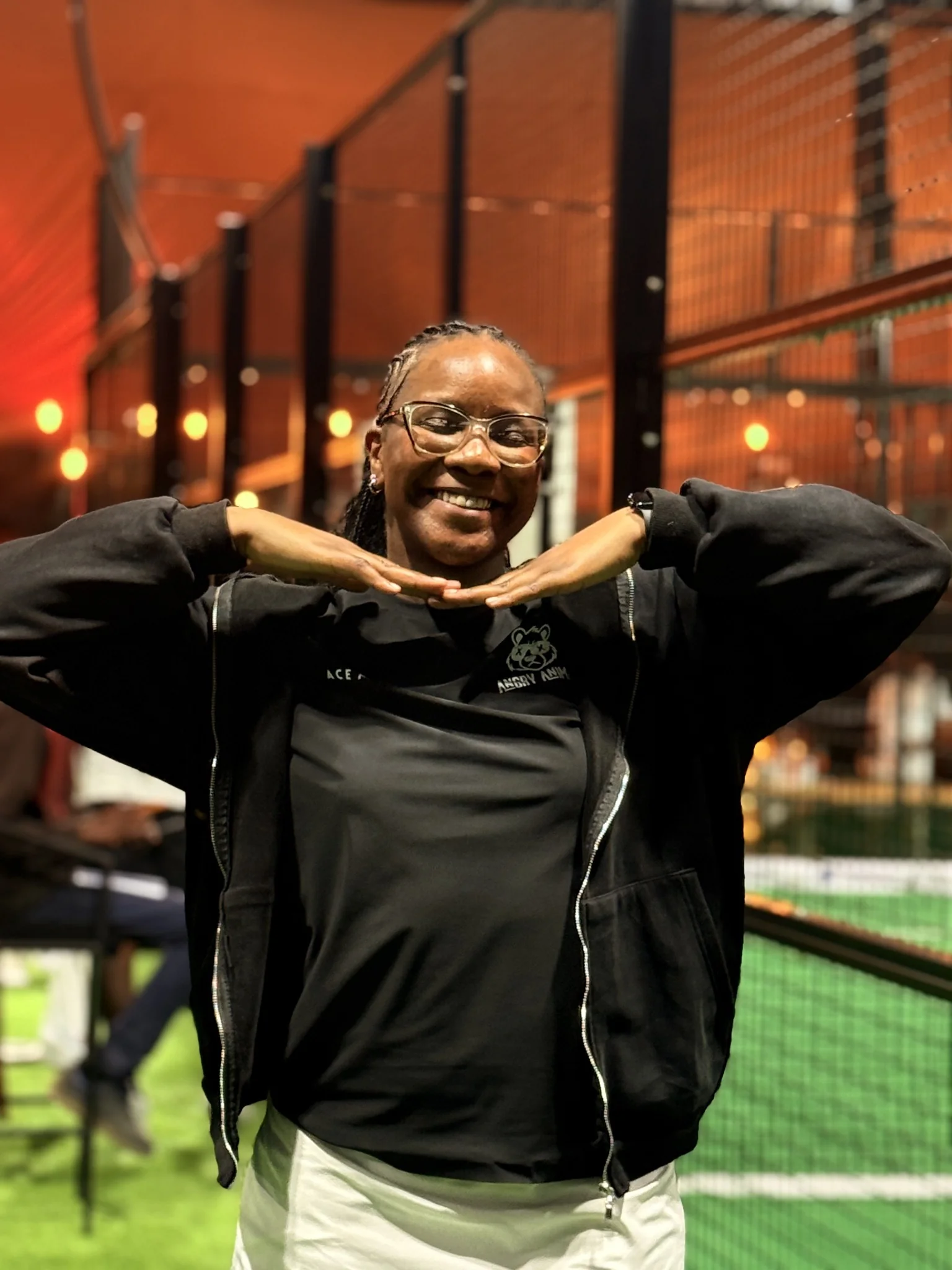 Tonia smiling at the padel court, holding her racket.